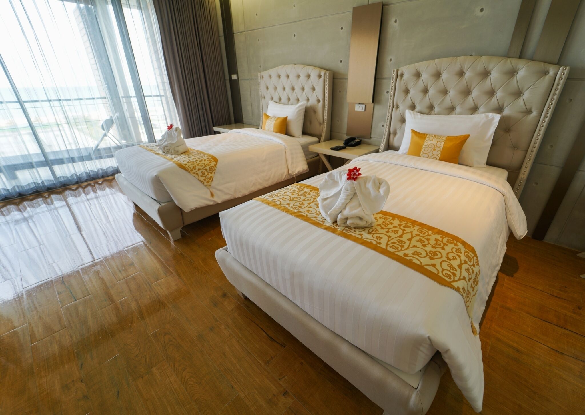 A hotel room with two beds, a large window, and a wooden floor.