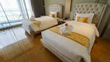 A hotel room with two beds, a large window, and a wooden floor.