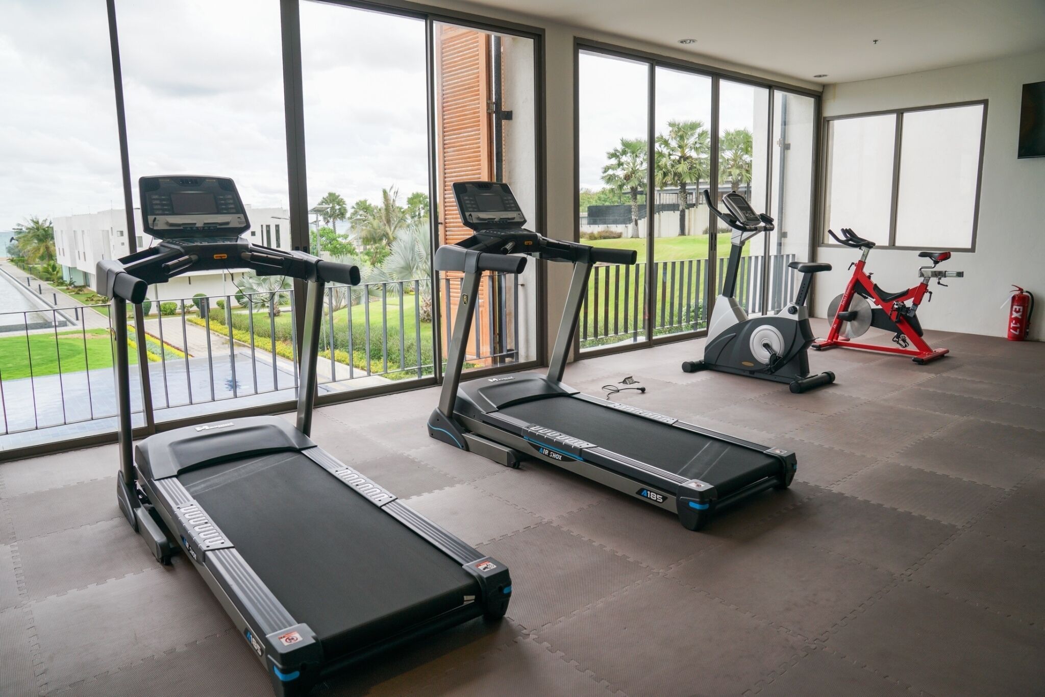 Un gimnasio con cintas de correr, una bicicleta estática y una bicicleta de ejercicio roja.