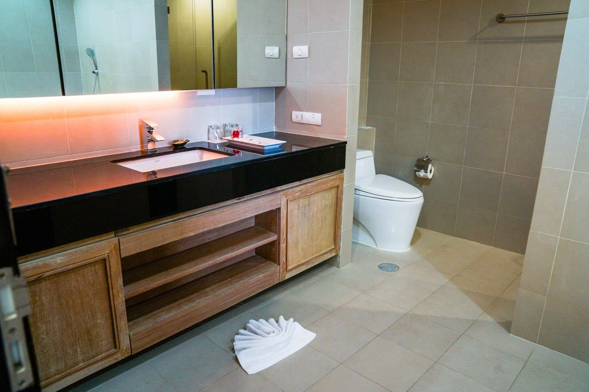 A bathroom with a black countertop, wooden cabinets, a white sink, and a toilet.