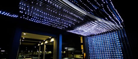 Un edificio moderno con un diseño de techo singular que incorpora numerosas luces.