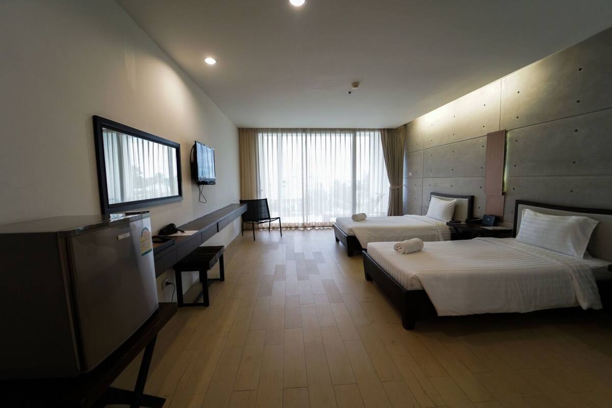 A hotel room with two beds, a desk, a television, and a minibar.