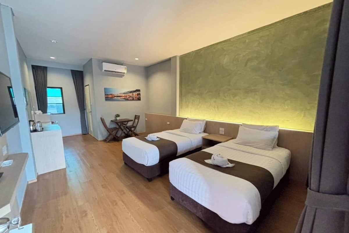 Ein Hotelzimmer mit zwei Betten, einem Schreibtisch, einem Stuhl und einem Fernseher.