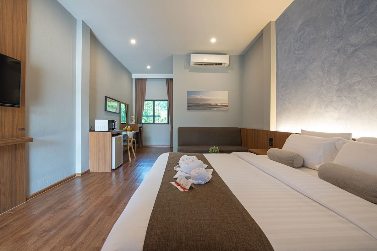 Ein Hotelzimmer mit Bett, Schreibtisch, Fernseher und Klimaanlage.