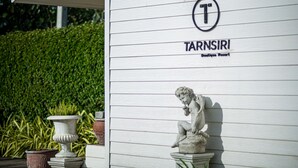 Een wit gebouw met het bord 'TARNSIRI Boutique Resort' en een beeld van een cherubijn.