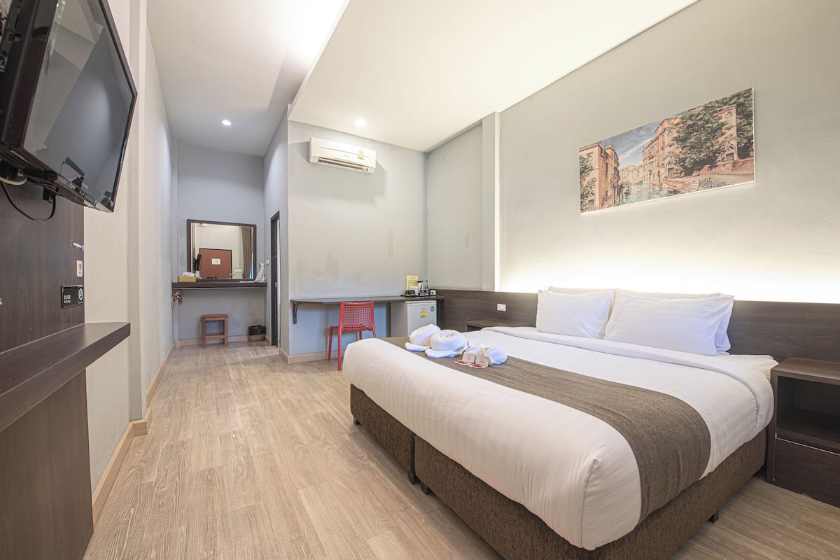 Ein Hotelzimmer mit einem Bett, einem Schreibtisch, einem Sessel, einem Fernseher und einer Klimaanlage.