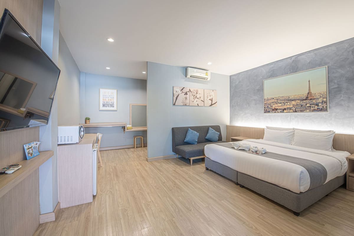 Ein modernes Hotelzimmer mit Bett, Schreibtisch, Fernseher und Kunstwerken an den Wänden.