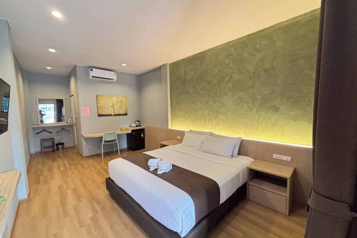 Ein Hotelzimmer mit Bett, Nachttisch, Schreibtisch mit Stuhl und einem großen Fenster.