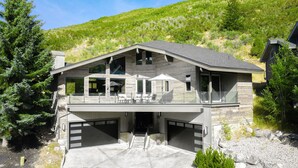 A modern two-story house with a garage, large windows, and a balcony.