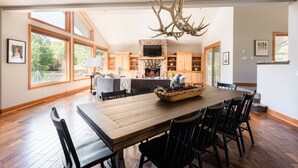 A spacious dining area with a large wooden table, black chairs, and a chandelier.