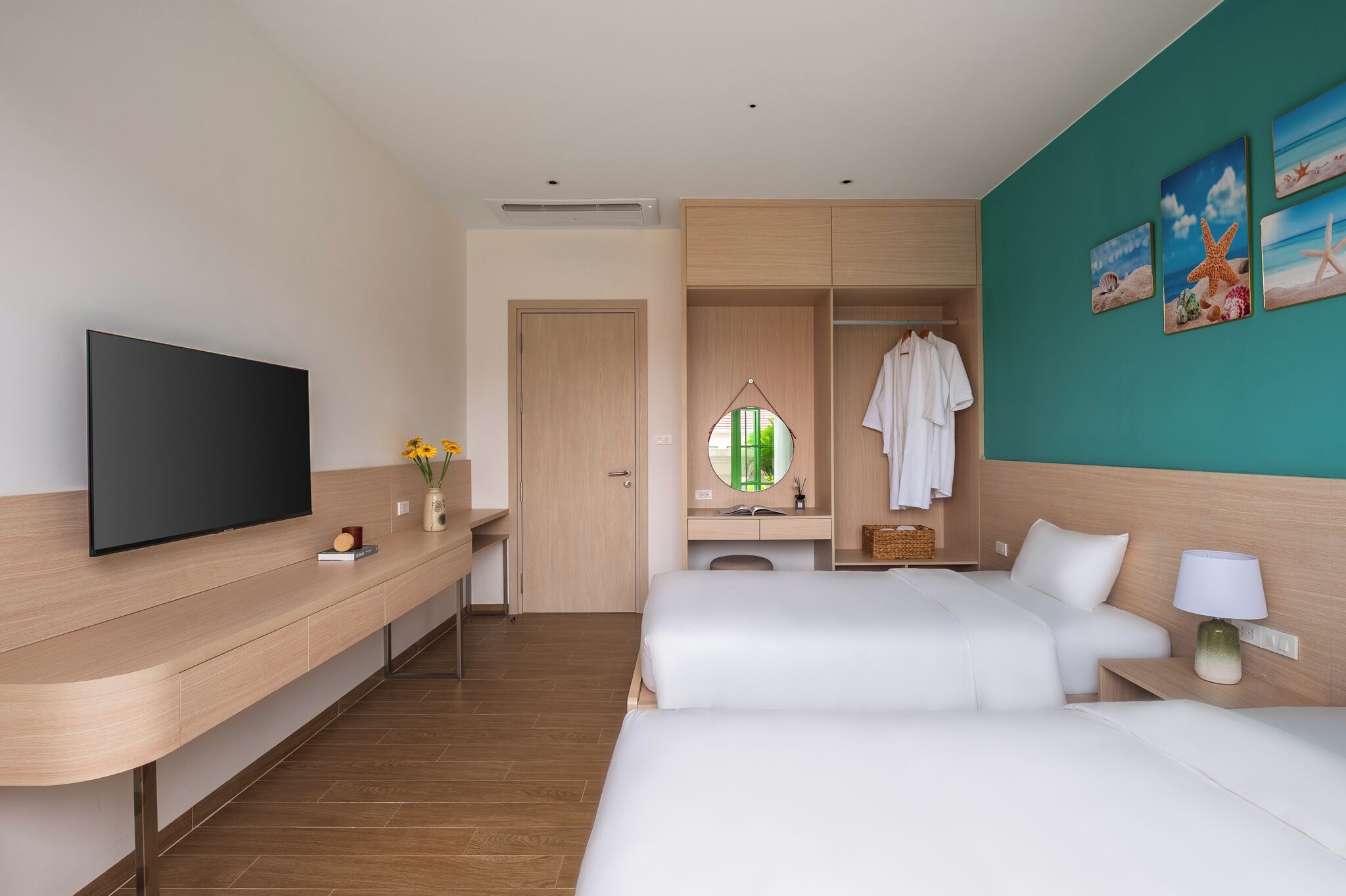 A hotel room with a TV, a desk, a bed, a wardrobe, and a bathroom mirror.