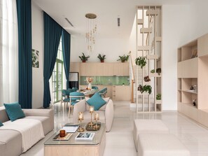 A modern living room with a sofa, coffee table, and a dining area with chairs. -  Ann Hotel & Spa Khem Beach PQ (Phu Quoc)