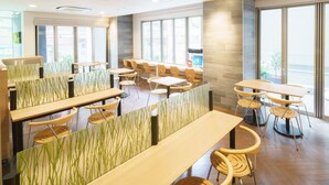 A modern dining area with wooden tables and chairs, partitioned by green-striped panels. - Super Hotel Midousuji Line Esaka (Suita)
