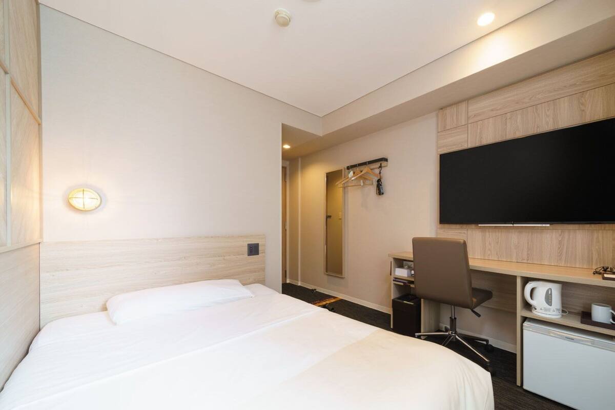 Een hotelkamer met een bed, een bureau, een stoel, een televisie en een koffiezetapparaat.