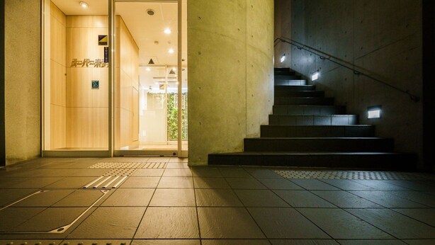 A hotel entrance with a wooden interior, a staircase, and a tiled floor. - Super Hotel Midousuji Line Esaka (Suita)
