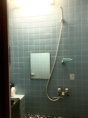 A bathroom with blue tiles, a showerhead, a soap dispenser, and a toilet. - Oasis Minamiyukigaya (Tokyo)