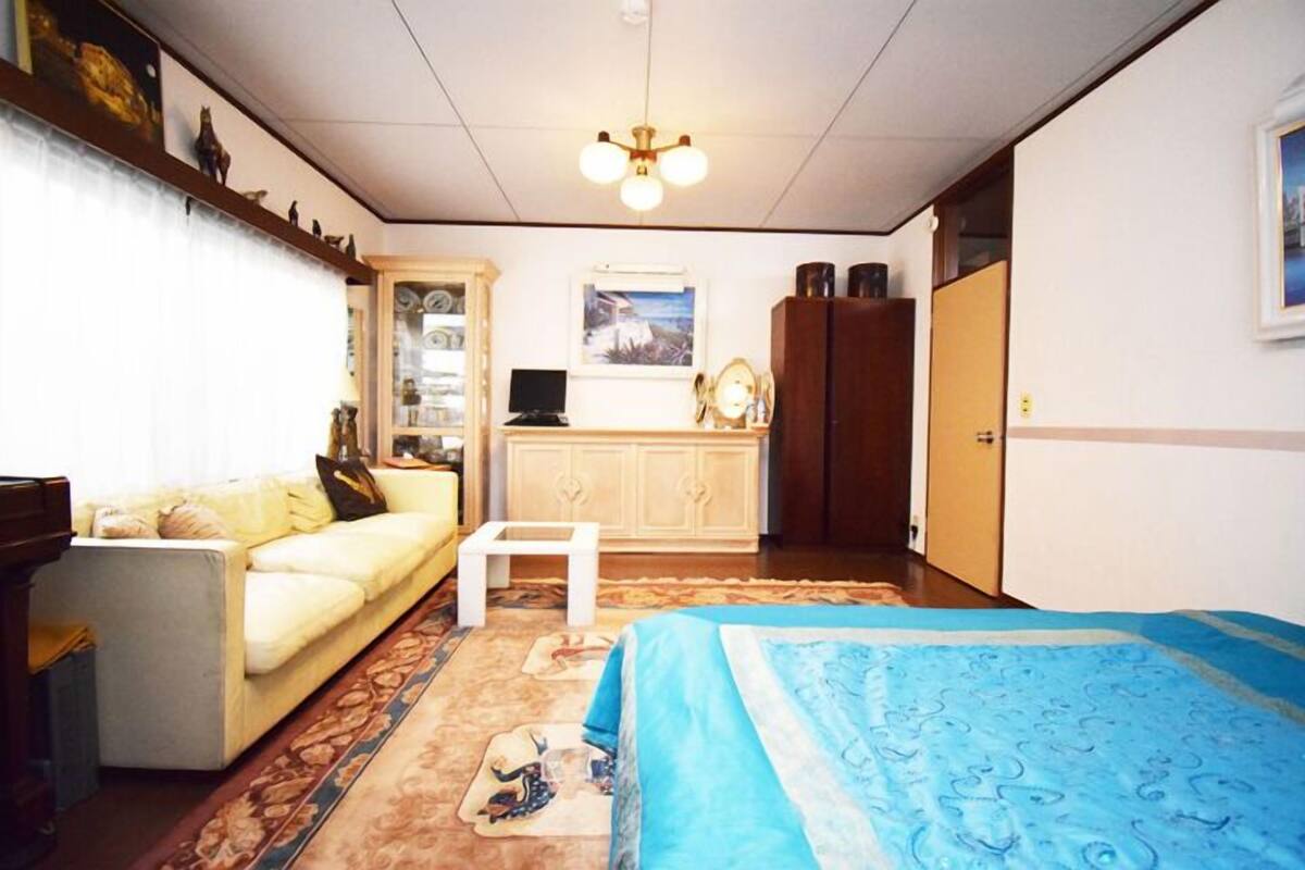 A room with a bed, a sofa, a small table, a cabinet, and a desk with a computer.
