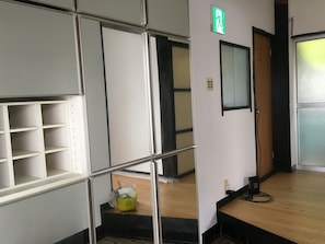 A hotel room with a wooden floor, a glass door, and a green exit sign.