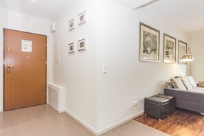 A modern living room with a grey sofa, a wooden door, and framed pictures on the wall. - RS2.29 - Sienkiewicz Residence (RS1, RS2) (Swinoujscie)