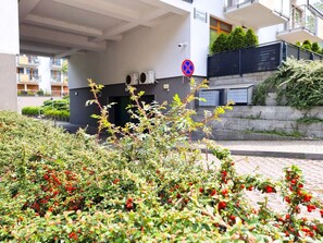 Un bâtiment moderne doté d’un espace extérieur couvert, de climatiseurs et d’un panneau indiquant qu’il est interdit de se garer.