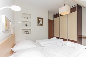 Una habitación de hotel con cama, armario y mesita de noche con lámpara.