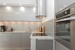 A modern kitchen with stainless steel appliances, a marble countertop, and recessed lighting.