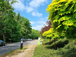 Un espace de stationnement avec des voitures, un panneau vert et des arbres.
