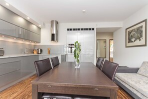 Una cocina moderna con comedor, que incluye una mesa de madera, sillas y un florero con plantas.
