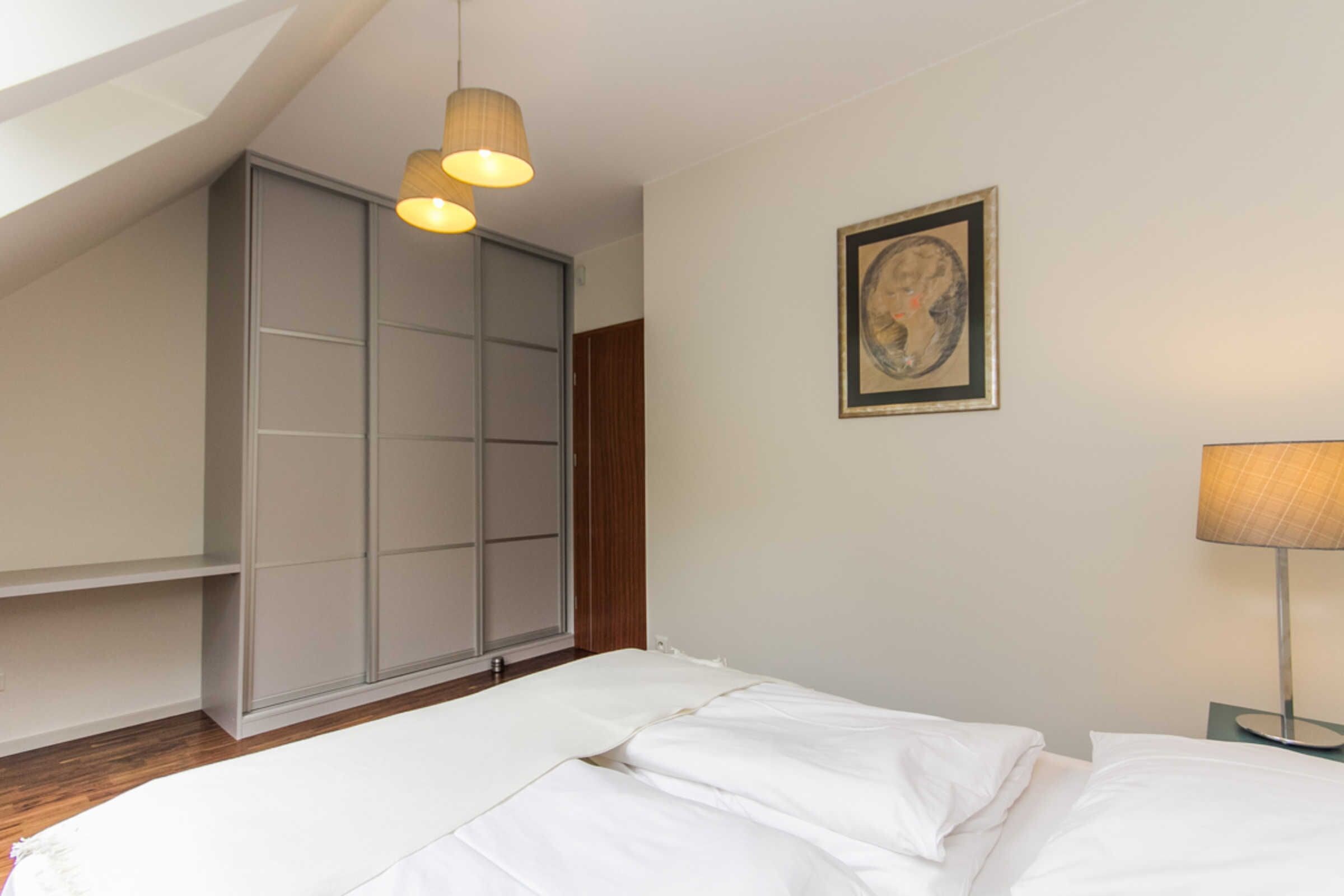 Une chambre à coucher avec un lit, une armoire, un tableau encadré au mur et une lampe sur pied.