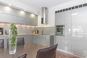 A modern kitchen with grey cabinets, stainless steel appliances, and a central island with seating. - RS2.29 - Sienkiewicz Residence (RS1, RS2) (Swinoujscie)