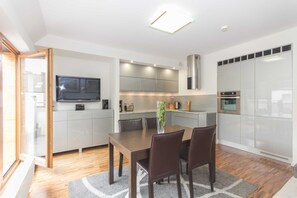 A modern kitchen with a dining area, built-in appliances, and a large window.