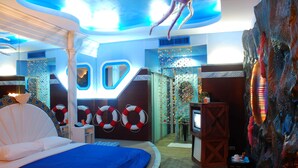 Quarto com cama, boias salva-vidas, televisão e um detalhe decorativo na parede.