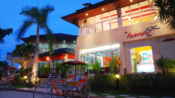 Um hotel moderno com fachada de vidro ampla, entrada visível e uma bicicleta estacionada na frente.