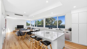 Una cocina moderna con una isla grande, taburetes de bar y un comedor con televisor y chimenea.