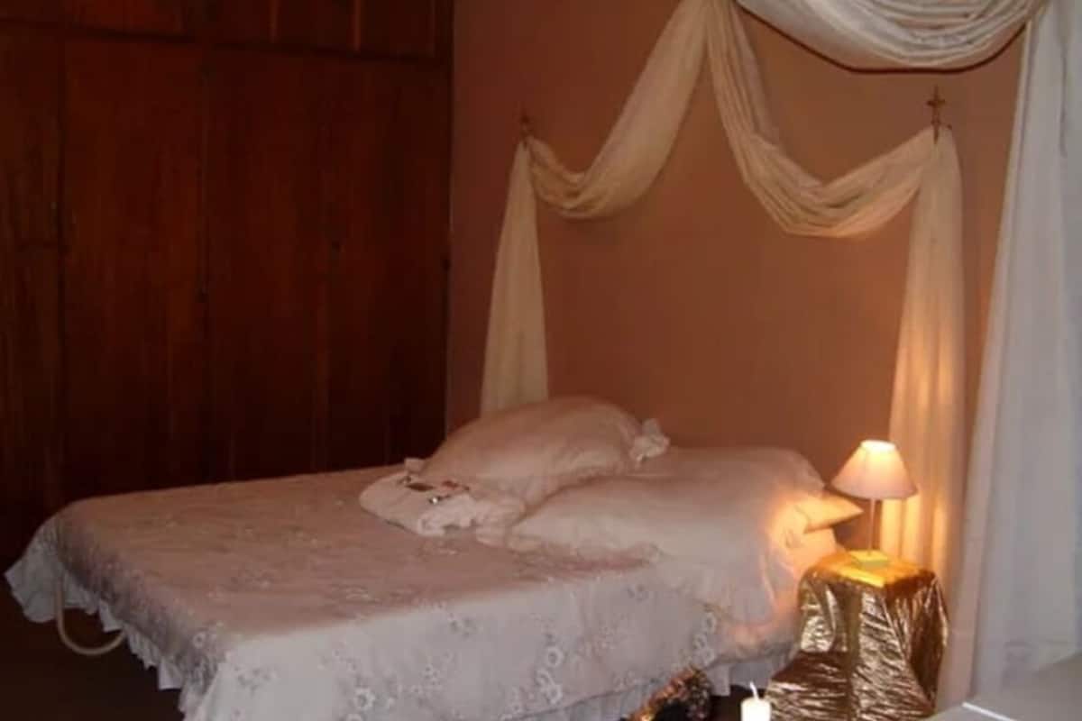 A bedroom with a bed, a nightstand, and a cross on the wall.