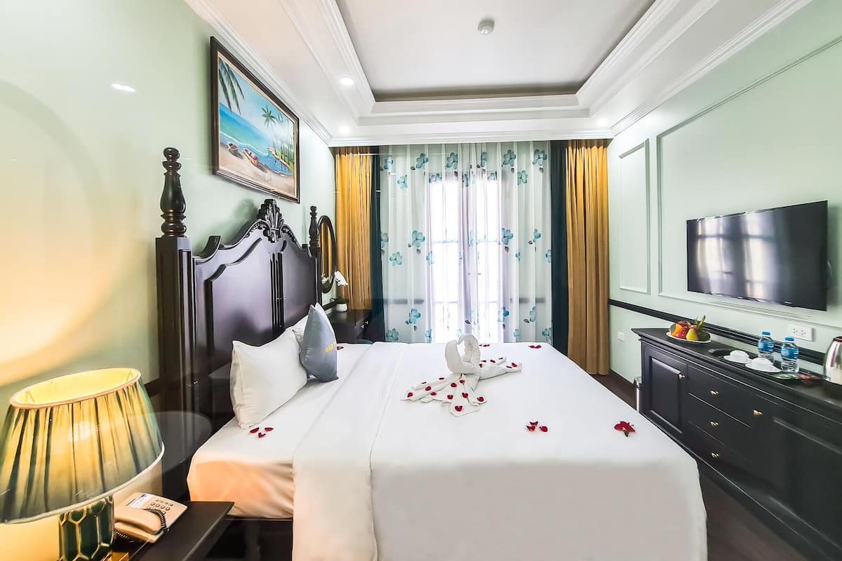 Una habitación de hotel con cama, televisión, cómoda y un cuadro en la pared.