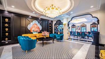 A luxurious lobby with a grand chandelier, a large painting, and a seating area with blue sofas.