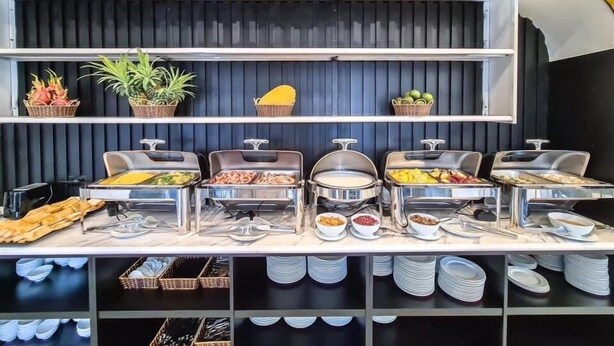 A buffet setup with various food items and utensils. - Dragon Hotel (Bai Chay)