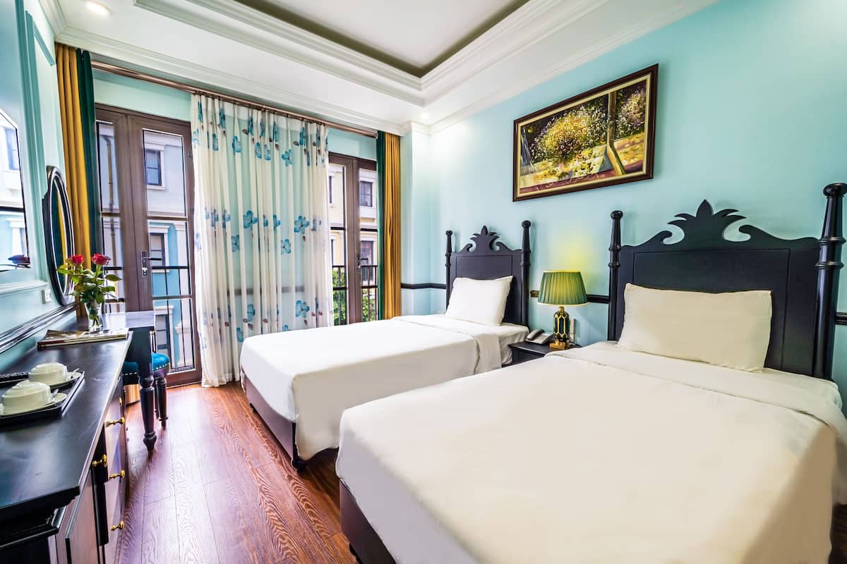 Habitación de hotel con dos camas, un escritorio con teléfono y una ventana con cortinas.