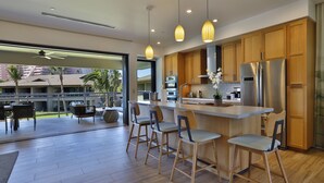 A modern kitchen with wooden cabinets, stainless steel appliances, and a central island with bar stools.