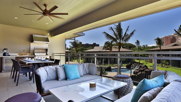 A spacious outdoor living area with a sofa, dining table, and kitchen area.