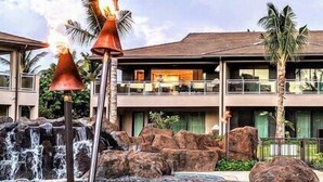 A hotel with a two-story structure, a waterfall feature, and a tropical garden.