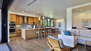Une cuisine moderne avec des meubles en bois, des appareils en acier inoxydable et un îlot central doté de tabourets de bar.