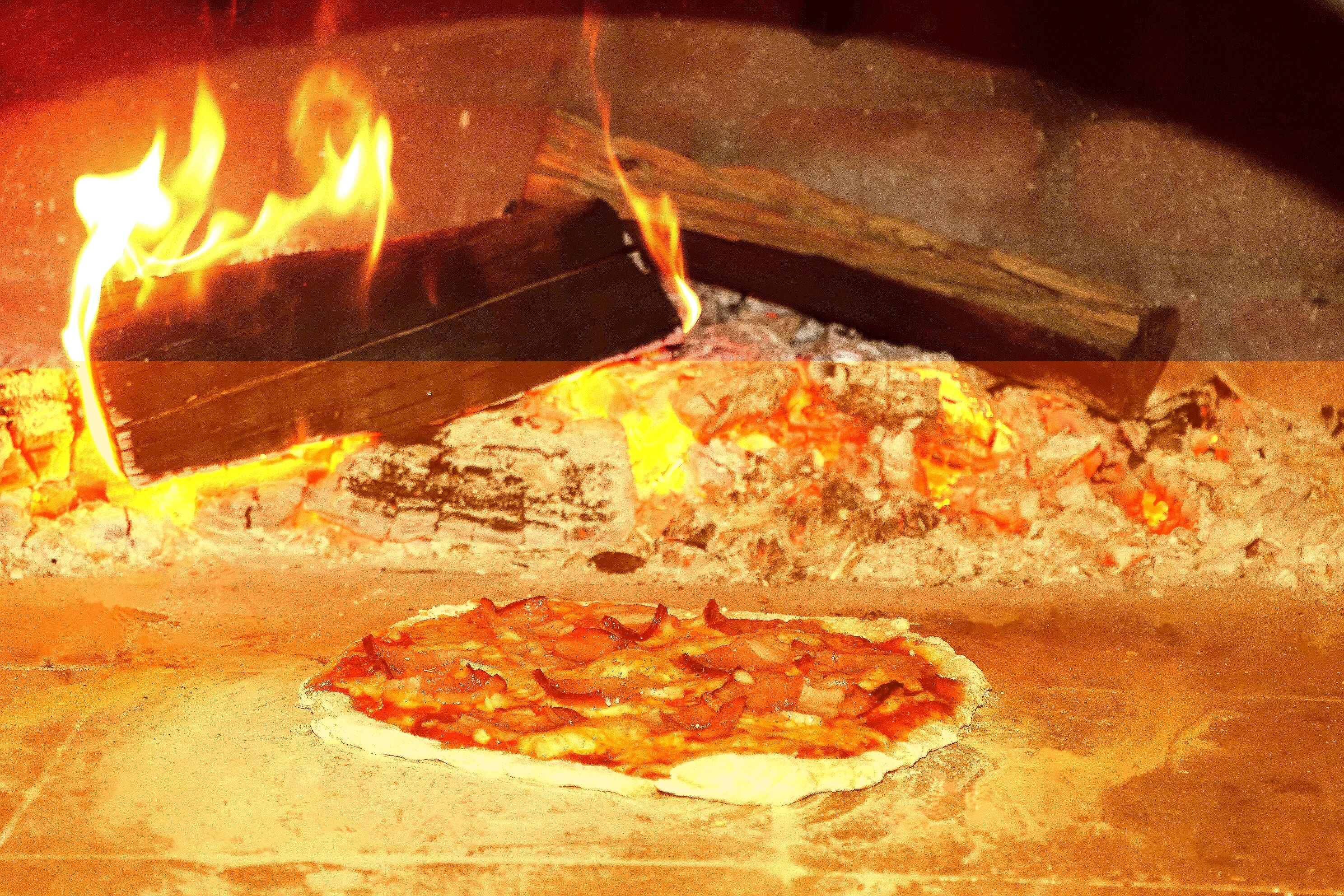 Un horno de pizza con una pizza en proceso de cocción.