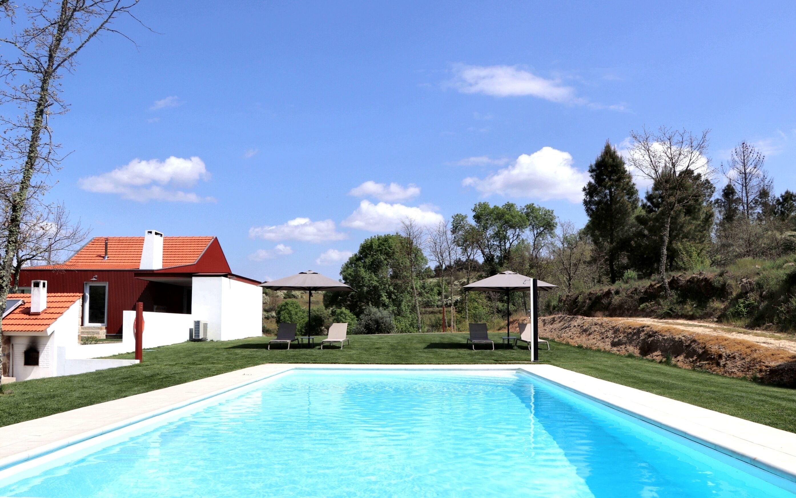 A swimming pool with lounge chairs and a gazebo, surrounded by a house and trees.