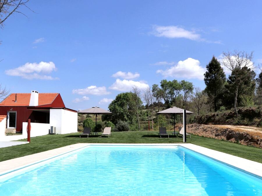 A swimming pool with lounge chairs and a gazebo, surrounded by a house and trees.