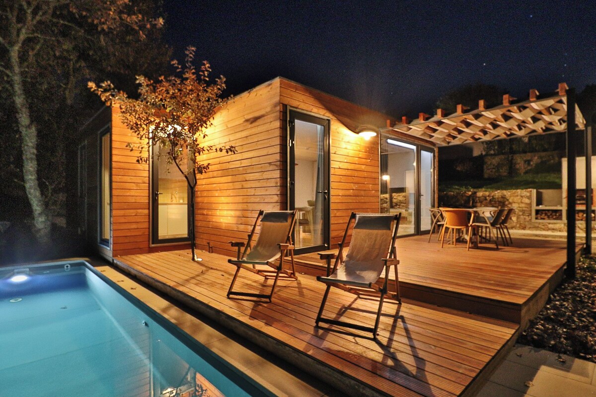 A wooden deck with a pool, lounge chairs, and a pergola.