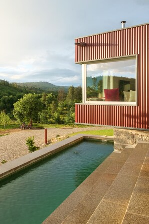 A modern building with a large window overlooking a pool and a scenic landscape. - Encosta do Sobreiro - Serra da Estrela (Fornos de Algodres)