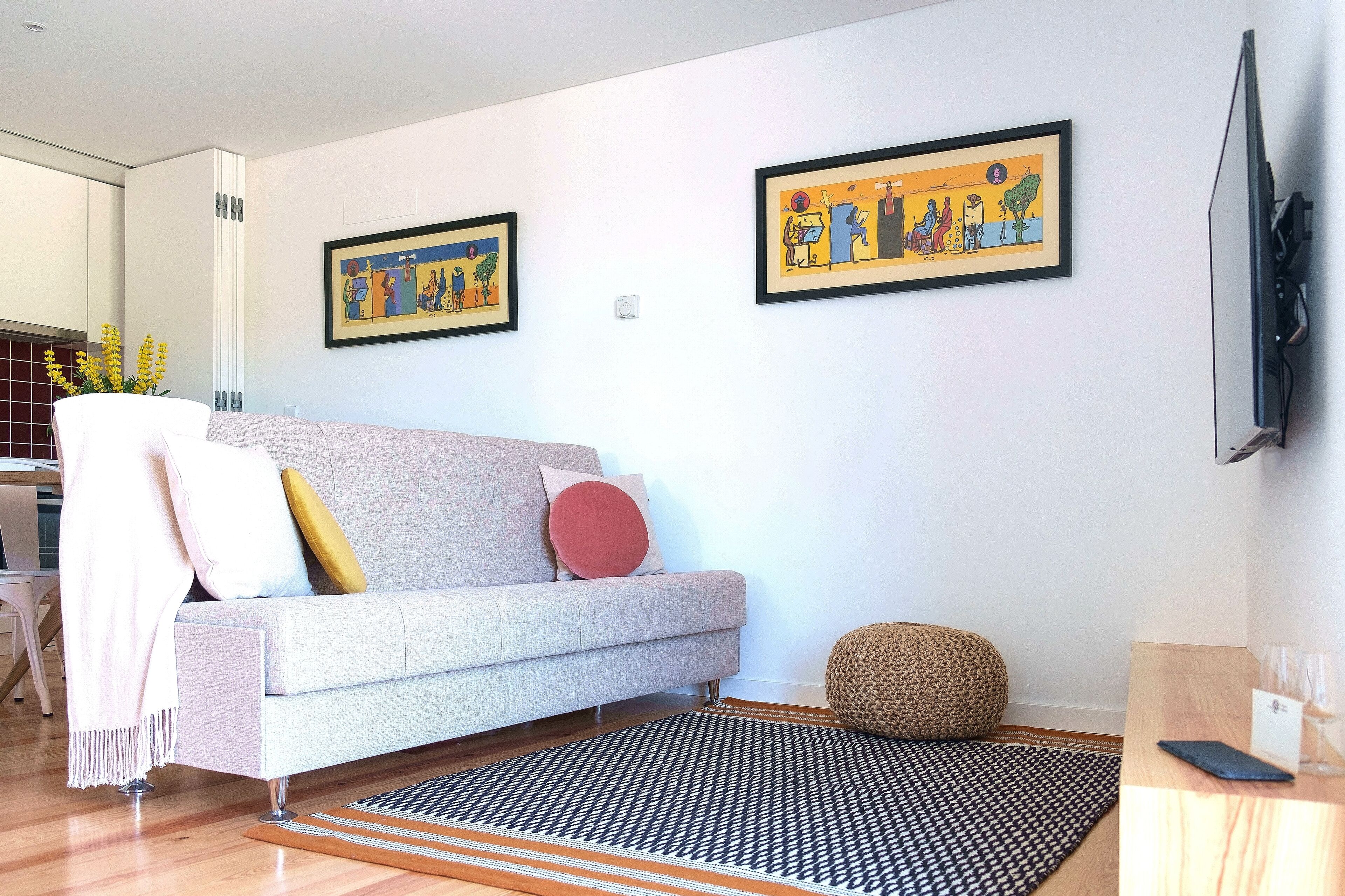 Una sala de estar moderna con un sofá gris, un tapete estampado y dos cuadros enmarcados en la pared.