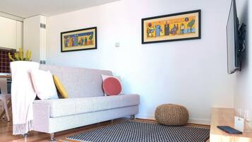 Una sala de estar moderna con un sofá gris, un tapete estampado y dos cuadros enmarcados en la pared.